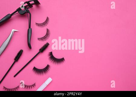 Flat lay composition with fake eyelashes, brushes and tools on pink background. Space for text Stock Photo
