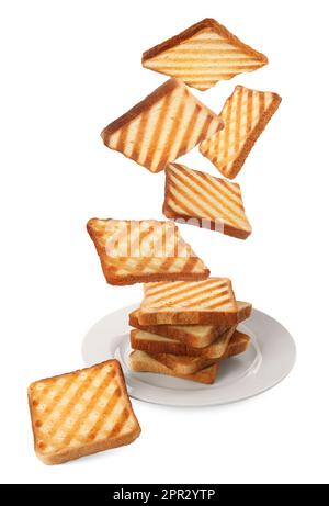 Delicious toasted bread falling into plate on white background Stock Photo