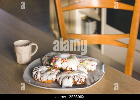 A plate of sweets with white icing, yellow red sprinkles Homemade Doughnuts, rosquillas, traditional anise donuts from Spain typically eaten in Easter Stock Photo