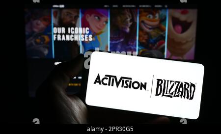 Person holding smartphone with logo of US video game company Activision Blizzard Inc. on screen in front of website. Focus on phone display. Stock Photo