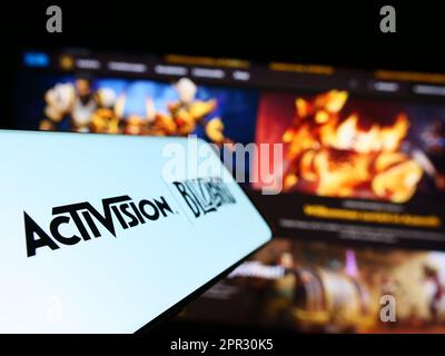 Cellphone with logo of American video game company Activision Blizzard Inc. on screen in front of website. Focus on center-left of phone display. Stock Photo