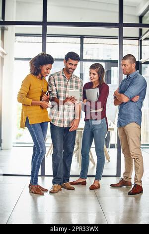 Big and bold is the way to go. a team of designers working together on a digital tablet in an office. Stock Photo