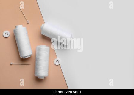 White thread spools, buttons and ball pins on color background Stock Photo