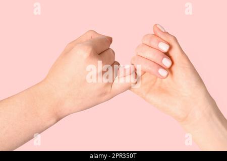 Hands of friends making pinky promise on color background Stock Photo