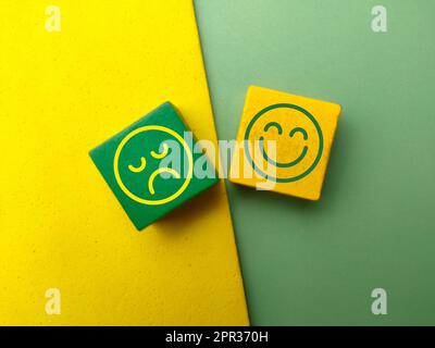 Top view colored wooden cube with the happy and unhappy face icons. Stock Photo