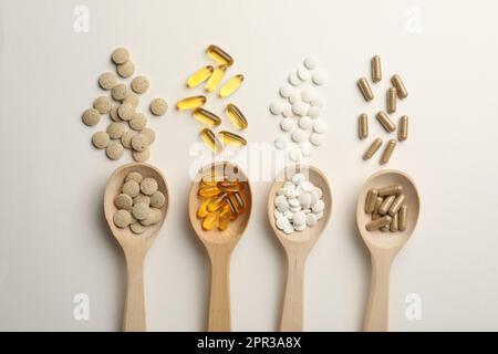 Wooden spoons and different dietary supplements on white background, flat lay Stock Photo