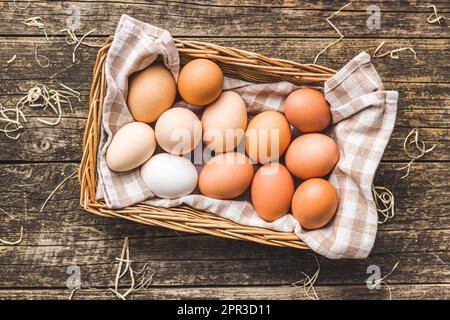 Whole chicken eggs in basket on the wooden table. Top view. Stock Photo