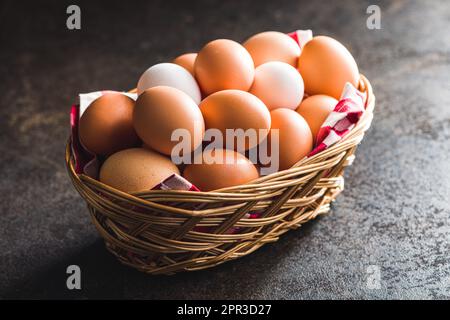 Whole chicken eggs in basket on the black table. Stock Photo