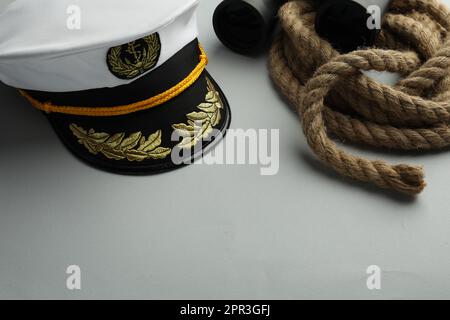 Peaked cap, rope and binoculars on light grey background. Space for text Stock Photo