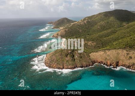 Aerial view of the tranquil blue waters of Rendezvous Beach in Antigua, featuring rocky shorelines and a picturesque landscape Stock Photo