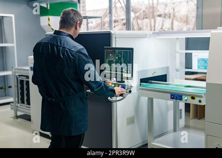 Perm, Russia - April 25, 2023: worker operates an automatic production line (PCB printer machine) in a workshop Stock Photo