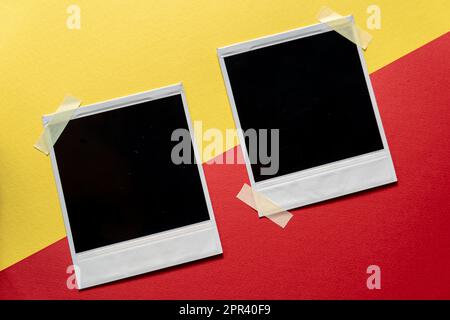 Download Blank photo frames template on red and yellow background. Blank square photo frames with tape on wall copy space Stock Photo