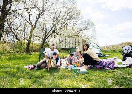 https://l450v.alamy.com/450v/2pr42bh/happy-young-family-with-four-children-having-fun-and-enjoying-outdoor-on-picnic-blanket-painting-at-garden-spring-park-relaxation-2pr42bh.jpg