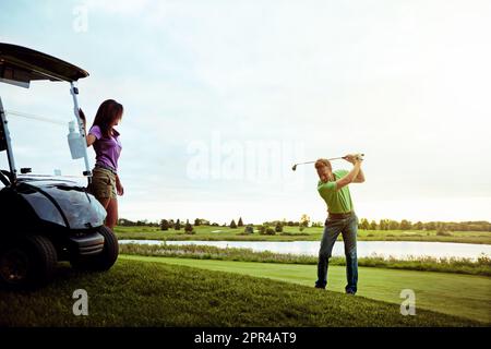 Nice form, babe. a man practicing his swing on the golf course. Stock Photo