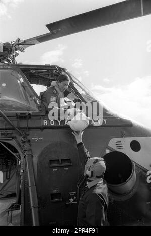 File photo dated 09/09/74 of Naval Lieutenant the Prince of Wales being handed his flying helmet by a ground crewman before going up for his first dual control flight with instructor Lieutenant Commander Alan MacGregor in a Royal Navy Wessex V helicopter. Issue date: Wednesday April 26, 2023. Stock Photo