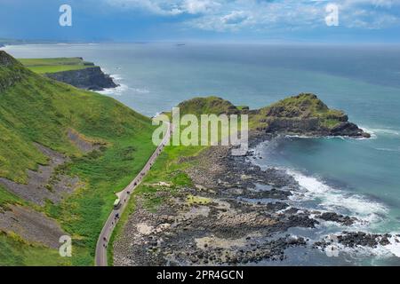 A bird's-eye Aerial view of a bus and a pedestrian path to the Giant's Causeway, with ocean view and blue sky in Northern Ireland, UK. Stock Photo
