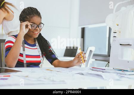 Happy African black woman working as Tailor Clothes Designer enjoy working happy smile at studio workshop Stock Photo