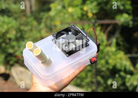 Air cooler device built at home using PC cooling fan fixed to a container that uses ice to cool the air held in the hand Stock Photo
