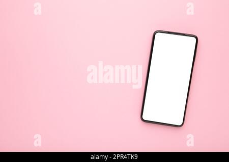 Black mobile smartphone with blank screen on pink background. Top view. Stock Photo