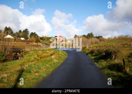long single track road approaching stop sign junction county donegal republic of ireland Stock Photo