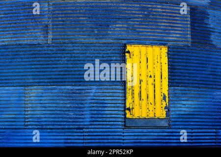 Old weathered corrugated metal building with yellow door Stock Photo