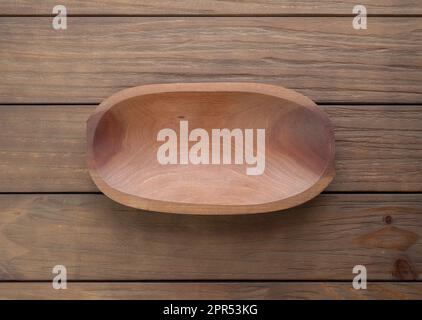 Empty handmade wooden bowl over wooden table. Stock Photo
