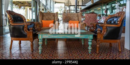 Fragment of the interior of a vintage beach restaurant or cafe on the tropical island of Koh Phangan, Thailand. Retro leather armchairs and a wooden o Stock Photo