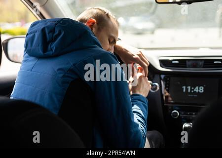 A young Asian man sleeping in his car, and he not driving for the safety concept of driving a car on the road. Falling asleep while driving a car Stock Photo