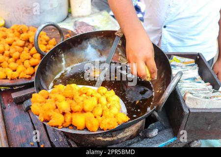 Male Vendor Preparing Street food Named Pakoda aka Pakora. Frying Roadside Snack in a Small Cart. Stock Photo