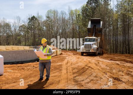 Construction engineer is experienced holds blueprint project in her hands when monitoring construction progress of work on construction site Stock Photo