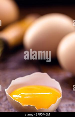 broken country chicken egg, visible yolk on wooden table, cooking with organic eggs Stock Photo