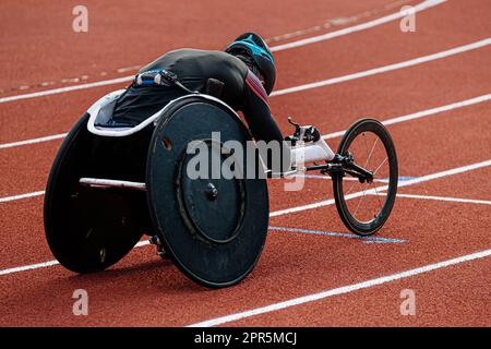 rear view para athlete in wheelchair racing riding on red track stadium, summer para athletics championships Stock Photo