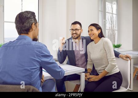 Professional male lawyer, financial advisor consulting happy family couple in office. Stock Photo