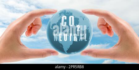 Carbon neutral concept. Hand holding CO2 neutral in globe map on blue sky and white clouds background. Environment day. Carbon neutral web banner. Environment issue. Global carbon neutrality concept. Stock Photo