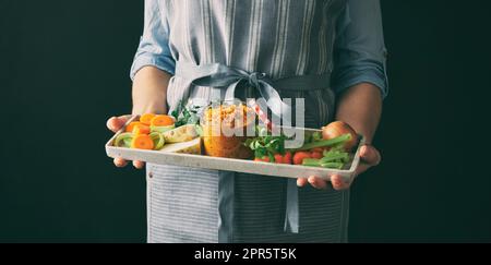 Faceless woman holding tray with vegetable conservation Stock Photo