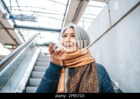 Senior woman in a trail station uses her smartphone Stock Photo