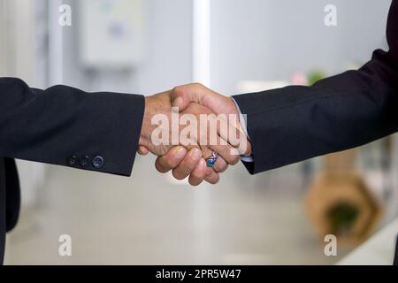 Business partners shaking hands in the modern office. Closeup Stock Photo