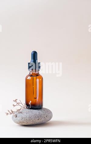 Amber glass dropper bottle with black lid on a podium on stones. Skincare products , natural cosmetic. Beauty concept for face and body care Stock Photo