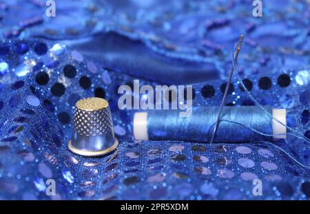 Blue Thread with needle and thimble on blue prom dress Stock Photo
