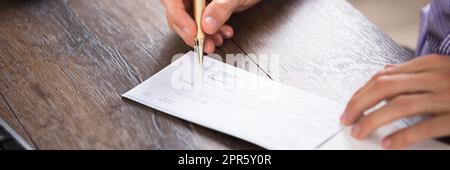 Businessperson's Hand Signing Cheque Stock Photo