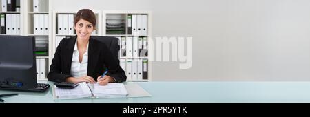 Confident Businesswoman Using Calculator At Office Desk Stock Photo