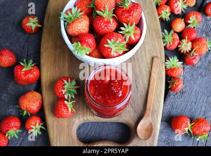 Homemade strawberry jam or marmalade in the glass jar and the fresh strawberries on the wooden rustic table Stock Photo