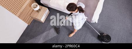 Female Janitor Cleaning Carpet With Vacuum Cleaner Stock Photo