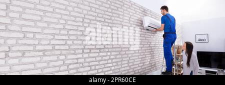 Male Technician Fixing Air Conditioner On Wall Stock Photo
