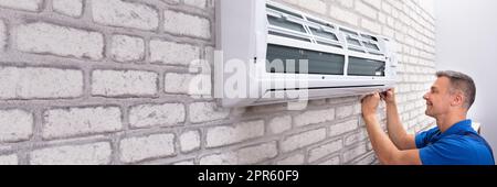 Technician Fixing Air Conditioner Stock Photo