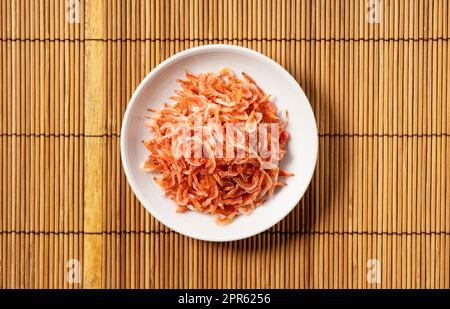 Dried sakura shrimps on a plate placed on a bamboo luncheon mat. Image of Japanese food. Stock Photo