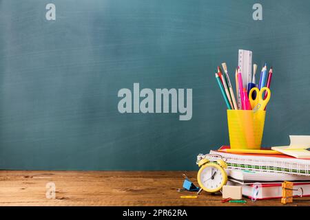 Many various school, office supplies on a wooden table on green background Stock Photo