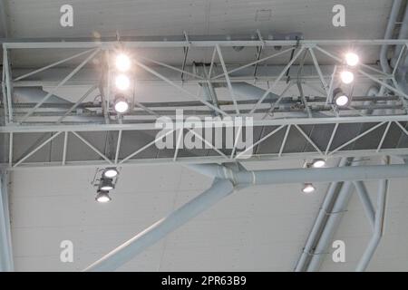 Ceiling with bright lighting in a modern warehouse, shopping center building, airport or other commercial real estate object. Directional LED lights on rails under the ceiling Stock Photo