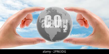 CO2 capture concept. Human hand holding CO2 in globe map on blue sky. Carbon capture and storage technology concept. Greenhouse gas. Carbon dioxide gas global air climate pollution. Environment issue. Stock Photo