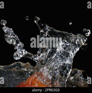 Isolated splashes of water on a black background. The fruit falls into the water. Stock Photo